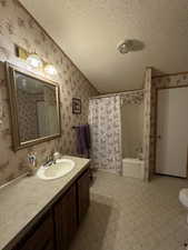 Full bathroom featuring tile patterned flooring, shower / bathtub combination with curtain, a textured ceiling, toilet, and vanity