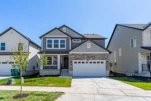 Craftsman inspired home with concrete driveway, a front yard, a garage, and stone siding