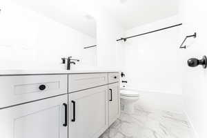 Full bathroom featuring vanity, baseboards, shower / tub combination, toilet, and marble finish floor