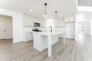 Kitchen featuring tasteful backsplash, light countertops, light wood-style flooring, and stainless steel appliances