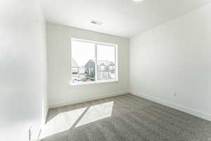 Empty room featuring carpet, visible vents, baseboards, and a textured ceiling
