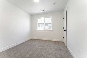 Spare room with a textured ceiling, baseboards, carpet, and visible vents