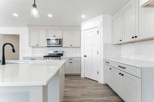 Kitchen featuring light wood-style floors, a sink, light countertops, and stainless steel appliances