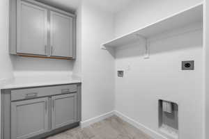 Washroom featuring washer hookup, hookup for an electric dryer, cabinets, and light hardwood / wood-style floors