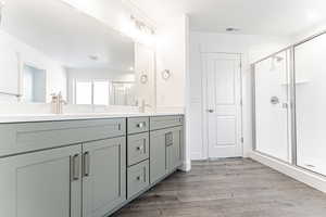 Full bath with visible vents, a stall shower, wood finished floors, and double vanity