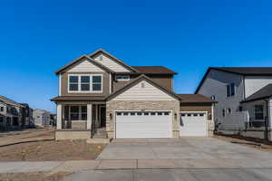 Craftsman-style home with a residential view, covered porch, driveway, stone siding, and an attached garage