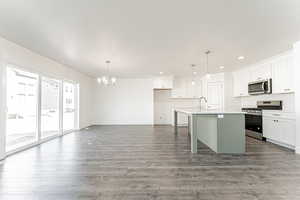 Kitchen with recessed lighting, wood finished floors, an island with sink, a chandelier, and stainless steel appliances