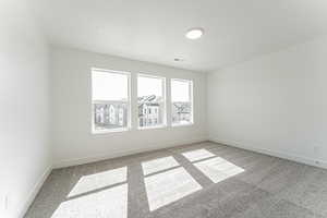 Unfurnished room featuring baseboards, visible vents, and light carpet