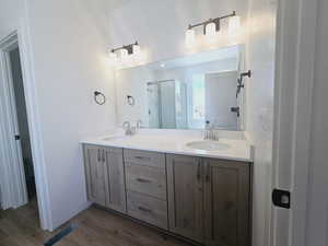 Bathroom with dual vanity and wood-type flooring