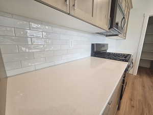 Kitchen featuring appliances with stainless steel finishes, decorative backsplash, light wood-type flooring, and light brown cabinetry