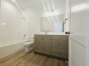 Full bathroom with vanity, shower / washtub combination, wood-type flooring, and toilet