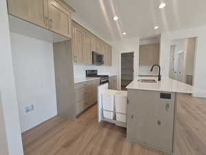 Kitchen with a kitchen island with sink, light hardwood / wood-style flooring, appliances with stainless steel finishes, and decorative backsplash