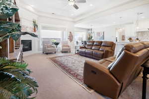 Carpeted living room with sink and ceiling fan with notable chandelier