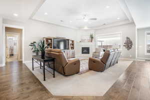 Living room with ceiling fan, a tray ceiling, and hardwood / wood-style flooring