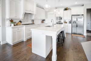 Kitchen featuring dark hardwood / wood-style flooring, white cabinets, an island with sink, sink, and appliances with stainless steel finishes