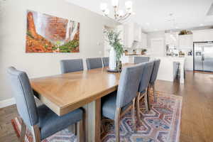 Dining space featuring dark wood-type flooring, sink, and an inviting chandelier