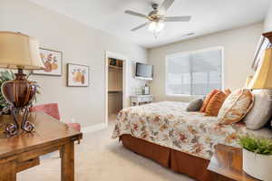 Bedroom featuring ceiling fan, light colored carpet, a closet, and a spacious closet