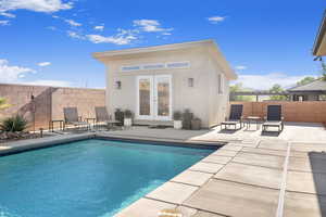 View of swimming pool with an outdoor structure, a patio area, and french doors