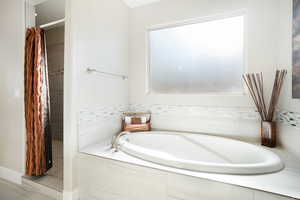 Bathroom featuring tiled tub and tile patterned floors