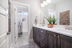 Bathroom with double vanity, tile patterned flooring, and shower / tub combo with curtain