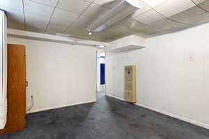 Empty room featuring a drop ceiling and carpet flooring