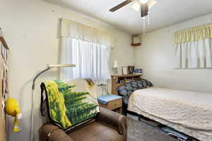 Bedroom with ceiling fan and a textured ceiling