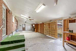 Misc room with vaulted ceiling, ceiling fan, and brick wall