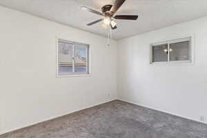 Carpeted empty room with ceiling fan and a textured ceiling