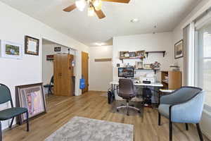 Office area with a textured ceiling, ceiling fan, and light hardwood / wood-style floors