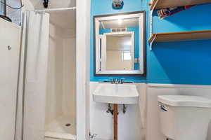 Bathroom featuring a shower with shower curtain, toilet, and sink