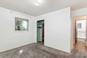 Unfurnished bedroom featuring carpet flooring, a textured ceiling, and a closet