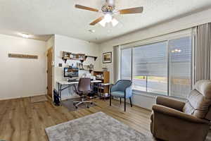 Office featuring a textured ceiling, ceiling fan, and light wood-type flooring