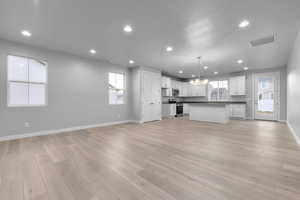 Kitchen with light hardwood / wood-style floors, a kitchen island, white cabinetry, and stainless steel appliances