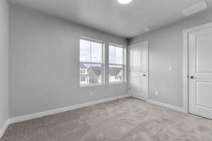 Unfurnished bedroom with light colored carpet and a textured ceiling