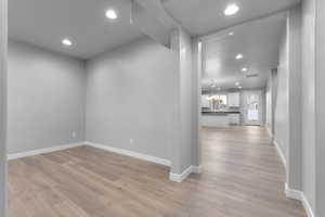 Hall featuring an inviting chandelier, a textured ceiling, and light wood-type flooring