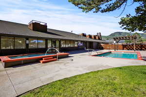 View of pool featuring a jacuzzi, a yard, and a pergola