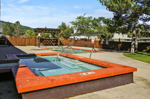 View of pool featuring a pergola and a hot tub