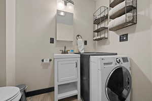 Laundry room with washer / dryer, sink, and wood-type flooring