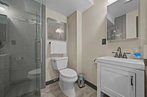 Bathroom with wood-type flooring, toilet, vanity, and an enclosed shower