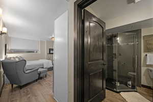 Bathroom with a shower with shower door, toilet, and hardwood / wood-style flooring