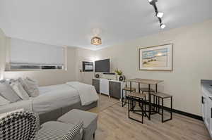 Bedroom with light hardwood / wood-style floors and rail lighting