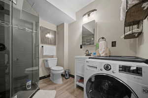 Interior space featuring hardwood / wood-style floors, washer / clothes dryer, walk in shower, toilet, and vanity