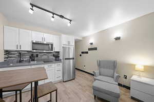 Kitchen with white cabinetry, rail lighting, and stainless steel appliances