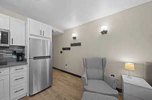 Kitchen with decorative backsplash, appliances with stainless steel finishes, light hardwood / wood-style flooring, and white cabinetry