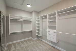 Walk in closet with light colored carpet