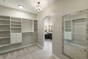 Walk in closet with light carpet and a chandelier