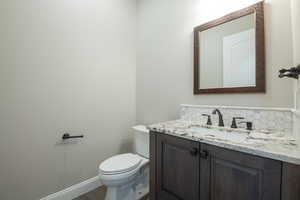 Bathroom featuring vanity, decorative backsplash, and toilet