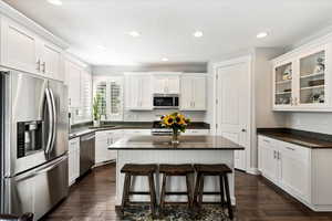 Kitchen featuring white cabinetry, dark hardwood / wood-style floors, appliances with stainless steel finishes, and a kitchen island