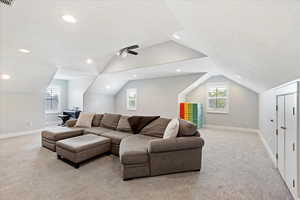 Carpeted living room with a textured ceiling, ceiling fan, and vaulted ceiling