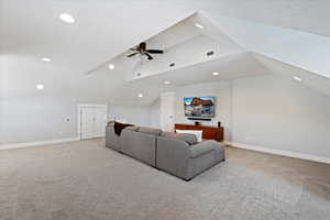 Carpeted living room with lofted ceiling and ceiling fan